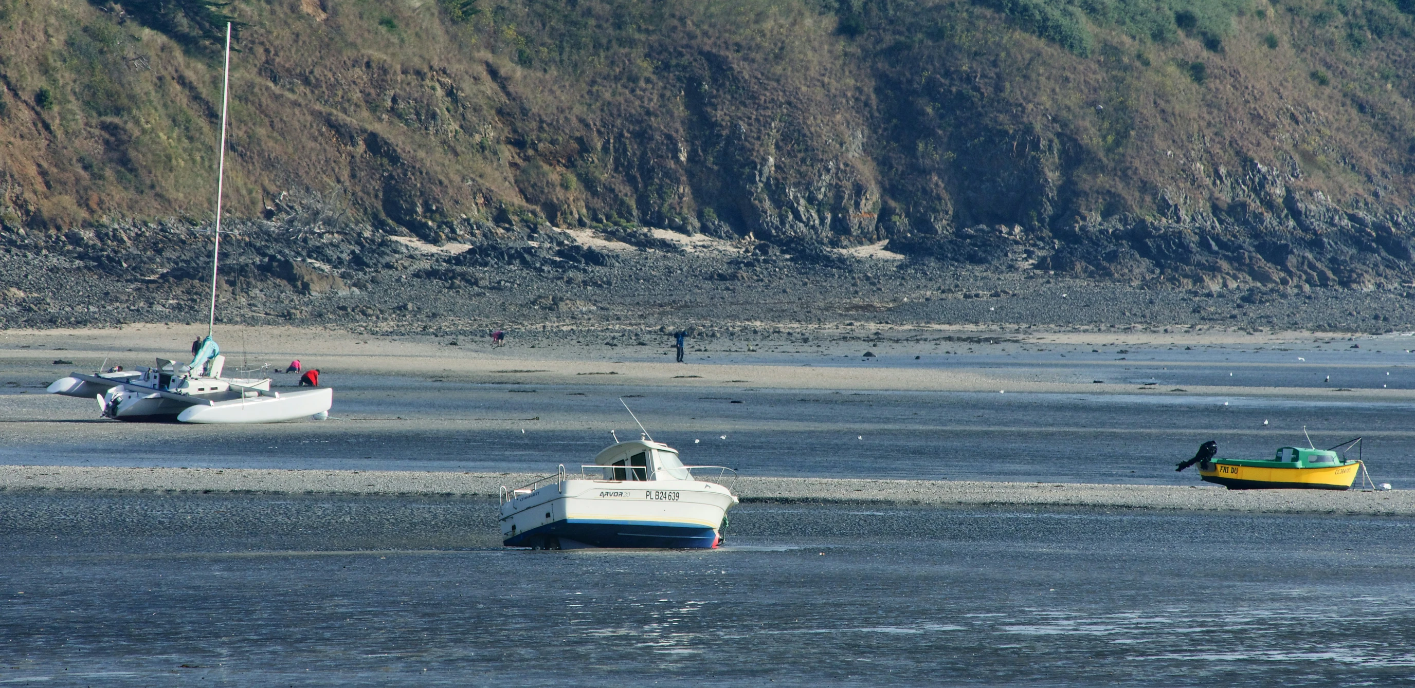 boats in the water near a rocky cliff