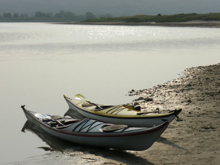 two kayaks sitting on top of a muddy beach