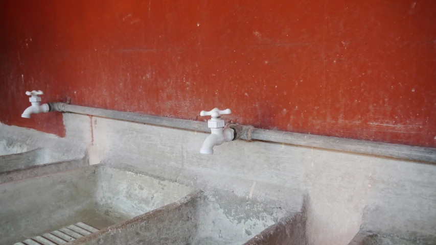 a red wall with white faucets sitting next to a sink