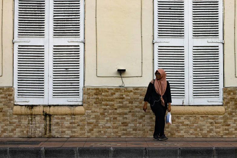 a woman standing in front of a large window next to a brick wall