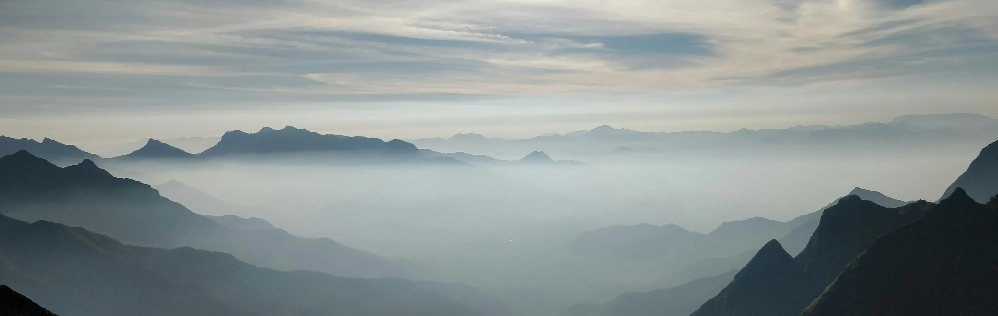 the sun shines on the mountains from a cloudy sky