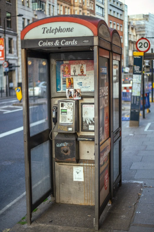 an old public phone that is on a sidewalk