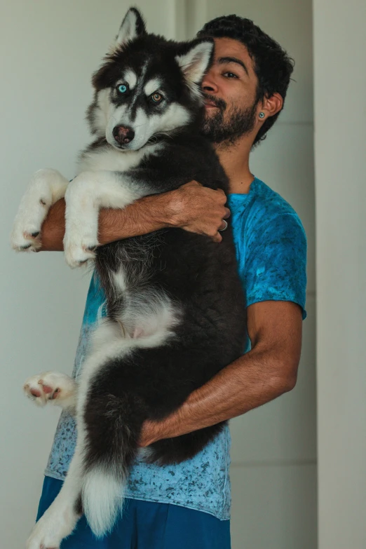 a man holding a husky dog up in the air