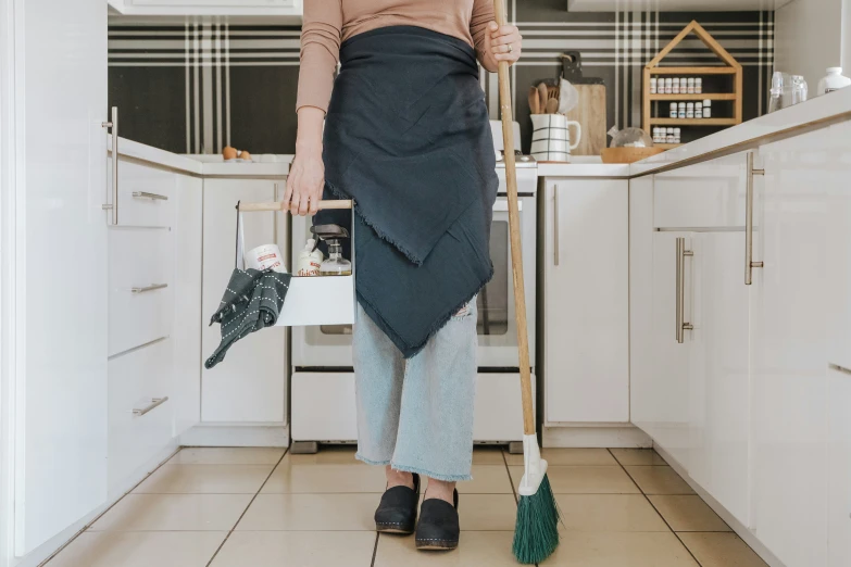 a lady in an apron with a broom and a black hat