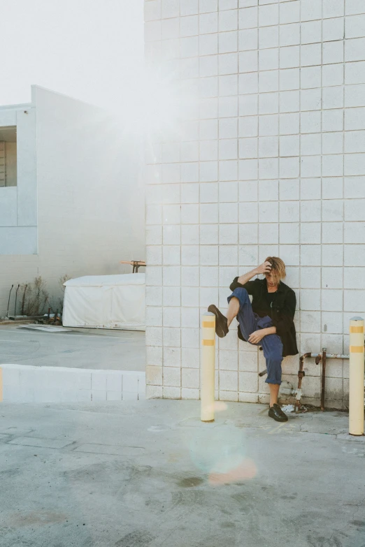 man sitting on post in front of building