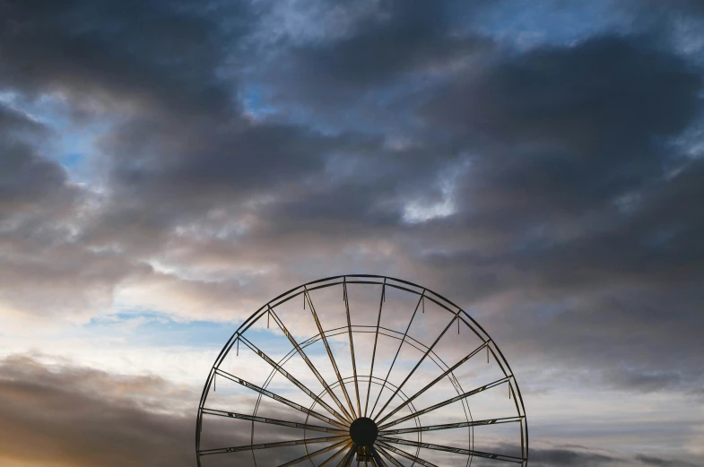 a large metal wheel with dark clouds in the background