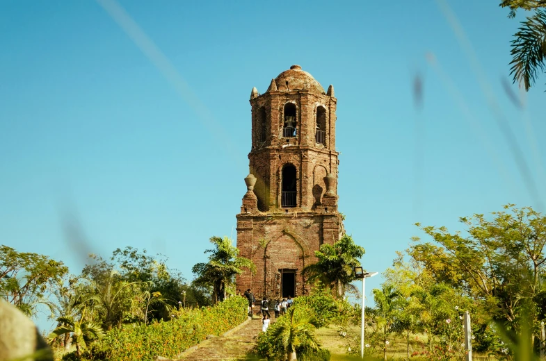 an old brick tower rises above trees and a hill