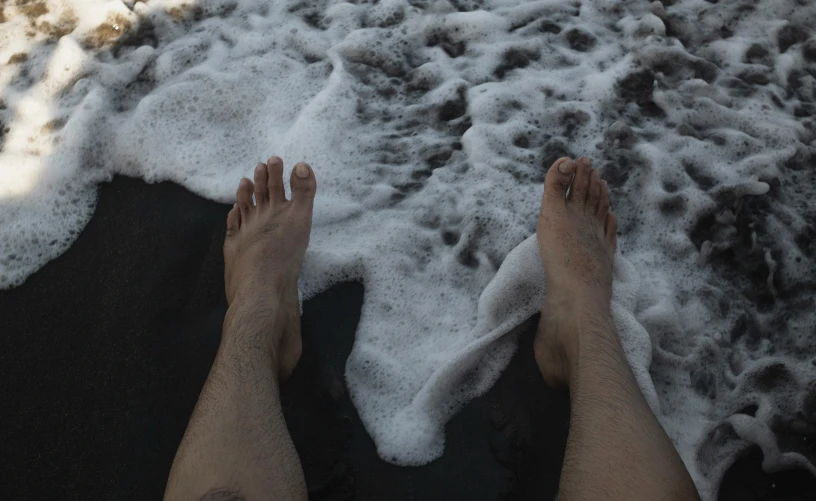 feet sticking out from the ocean foamy tide