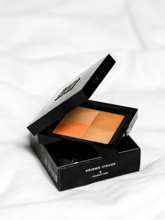 a compact face palette in a case on a bed