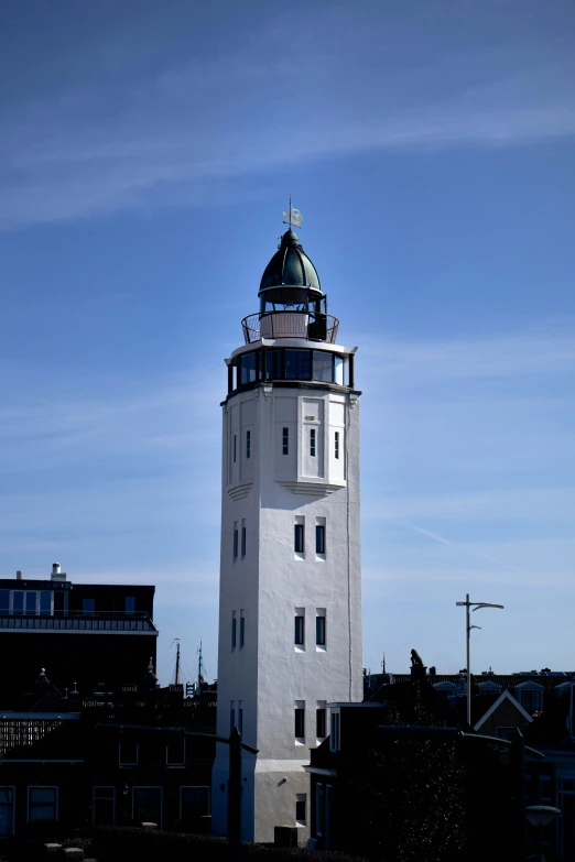 a tall tower stands in front of a building with a white and blue roof