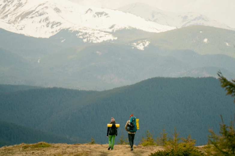 two hikers with backpacks hiking up a mountain