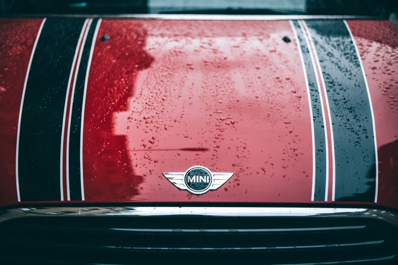 the front end of a classic red sports car with rain droplets on it