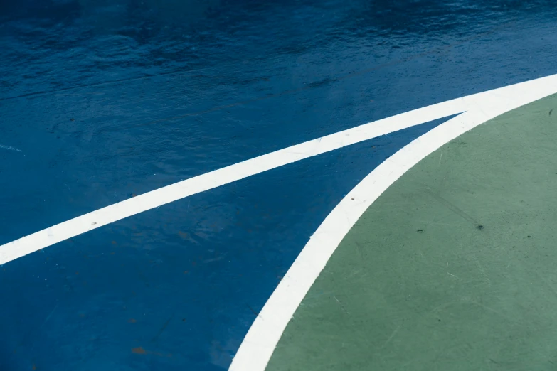 the floor of a tennis court with white lines and an object