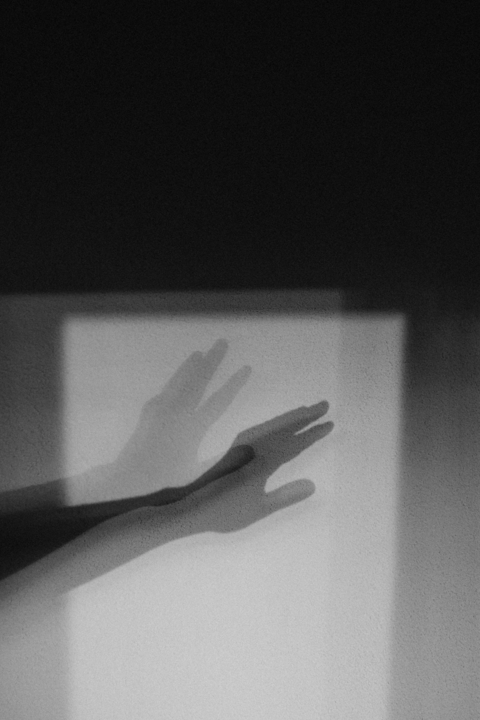 a hand reaching up in front of a window