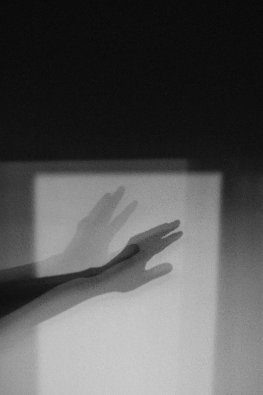 a hand reaching up in front of a window