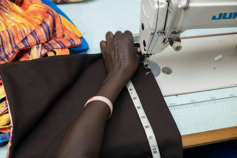 a person is sewing on a black cloth