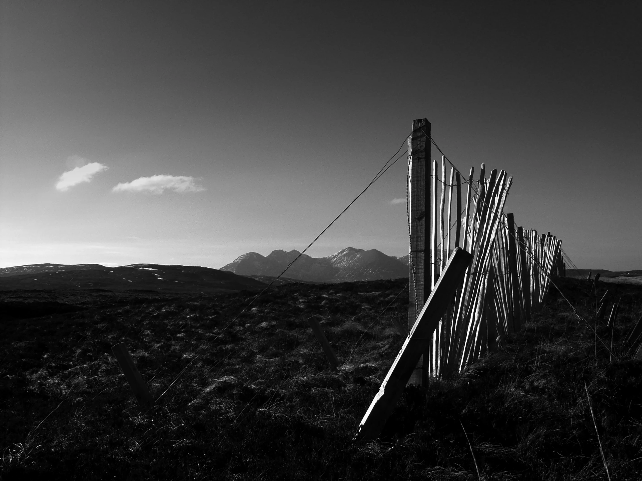 a line of fence with barbed wire and mountains in the distance