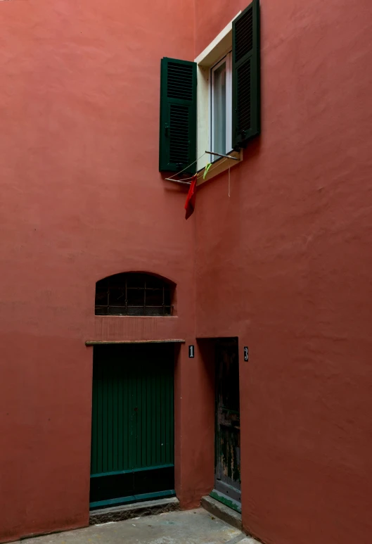 the building is pink, the windows have green shutters