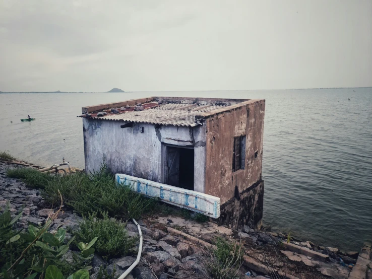 an old boathouse sits on the edge of a body of water