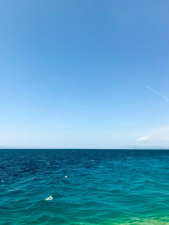 some very pretty blue ocean with a big kite flying in the sky