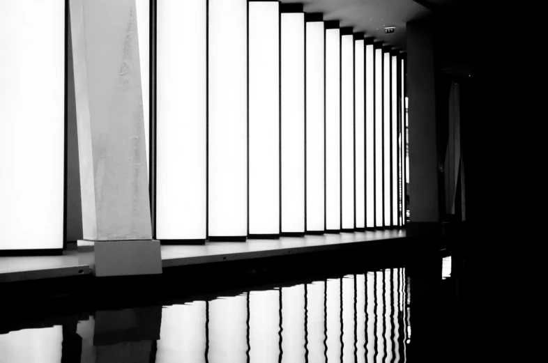 a hallway filled with lots of white windows next to a wall