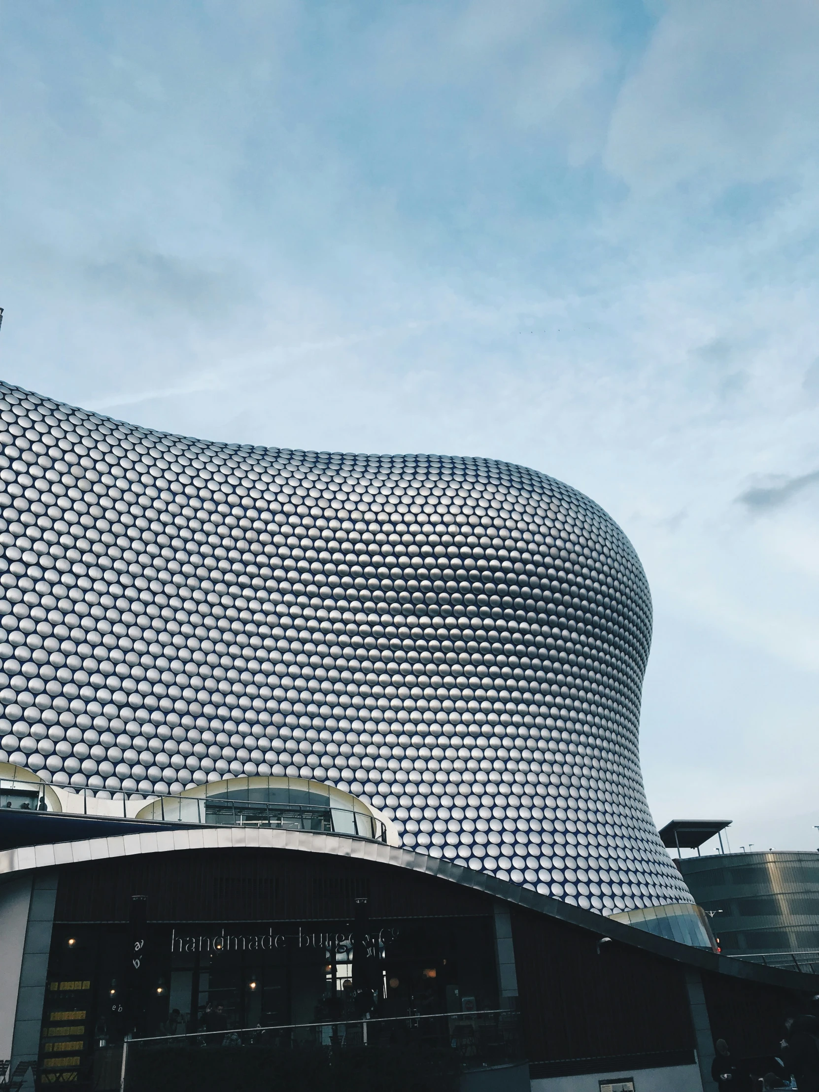 a huge, silver curved building with a clock tower at the top