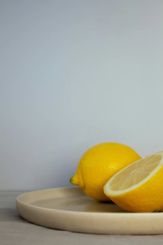 two yellow lemons are sitting on a wooden plate