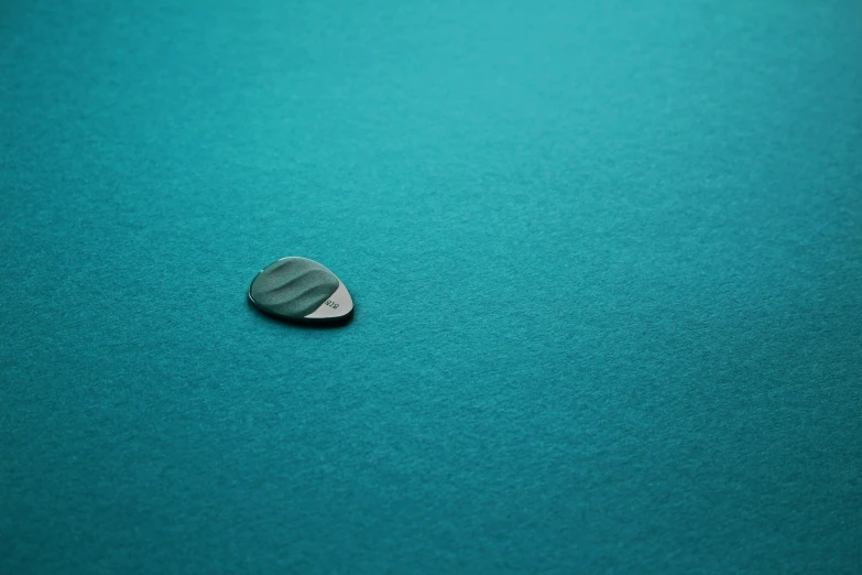 the back of a black and white round object sitting on a turquoise colored surface