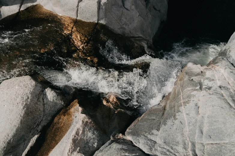 water flowing over rocks in the wilderness next to a rocky hill