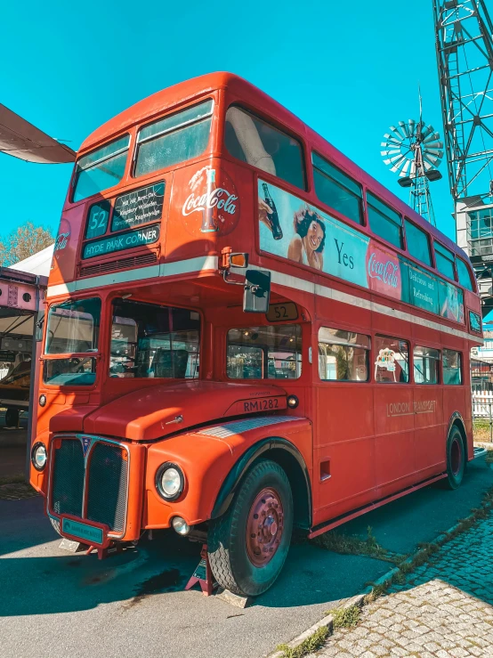 an old red double decker bus parked in front of a carnival ride