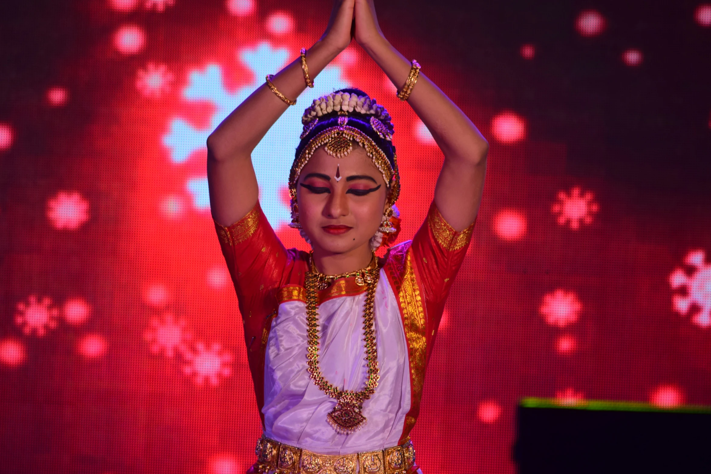 an indian belly dancer in costume performing in front of a red background