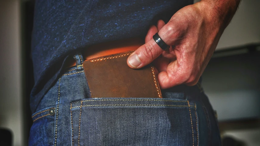 the mans hand is touching a leather wallet