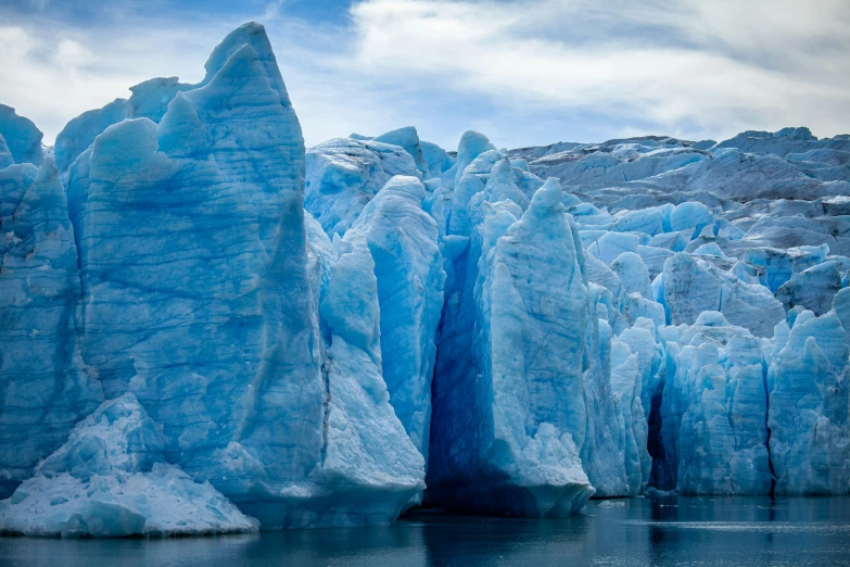 a glacier wall in front of blue water