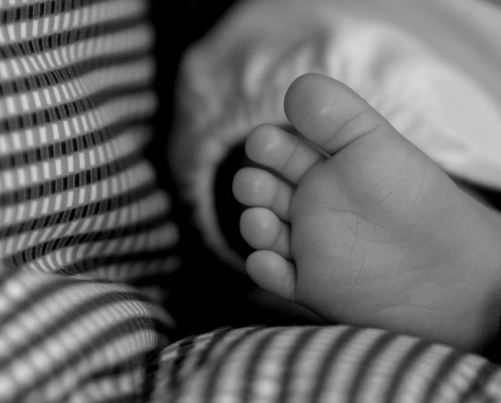 a hand holding a baby's hands in a black and white po