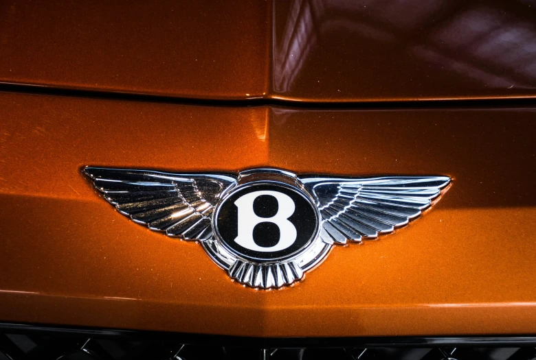 a bentley emblem on the hood of an orange sports car