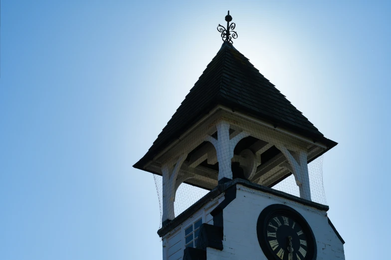 a clock tower with a sun shining in the background