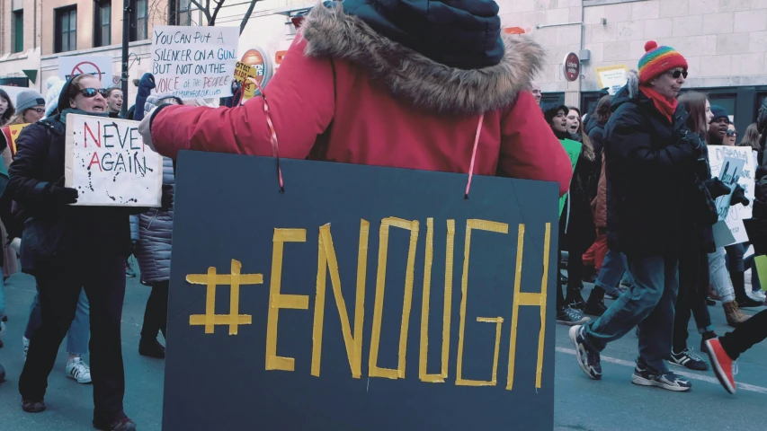 people walking in a street with signs attached to their backs