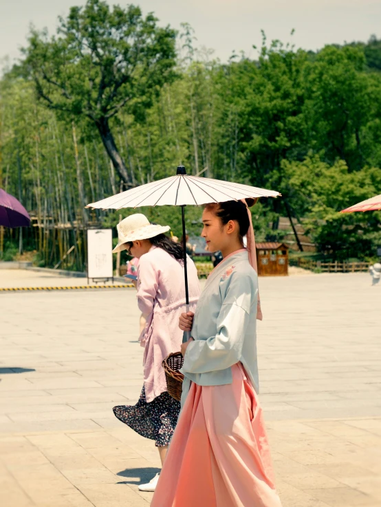 two women walking across a cement surface next to trees