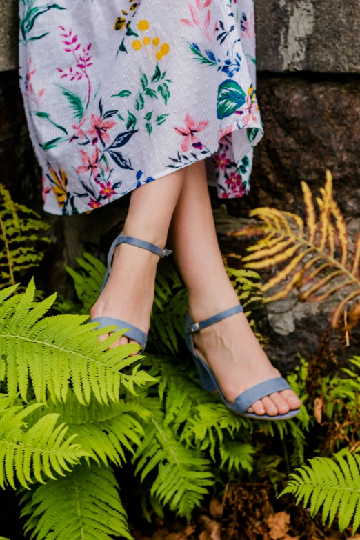 a woman in blue shoes sitting on some plants