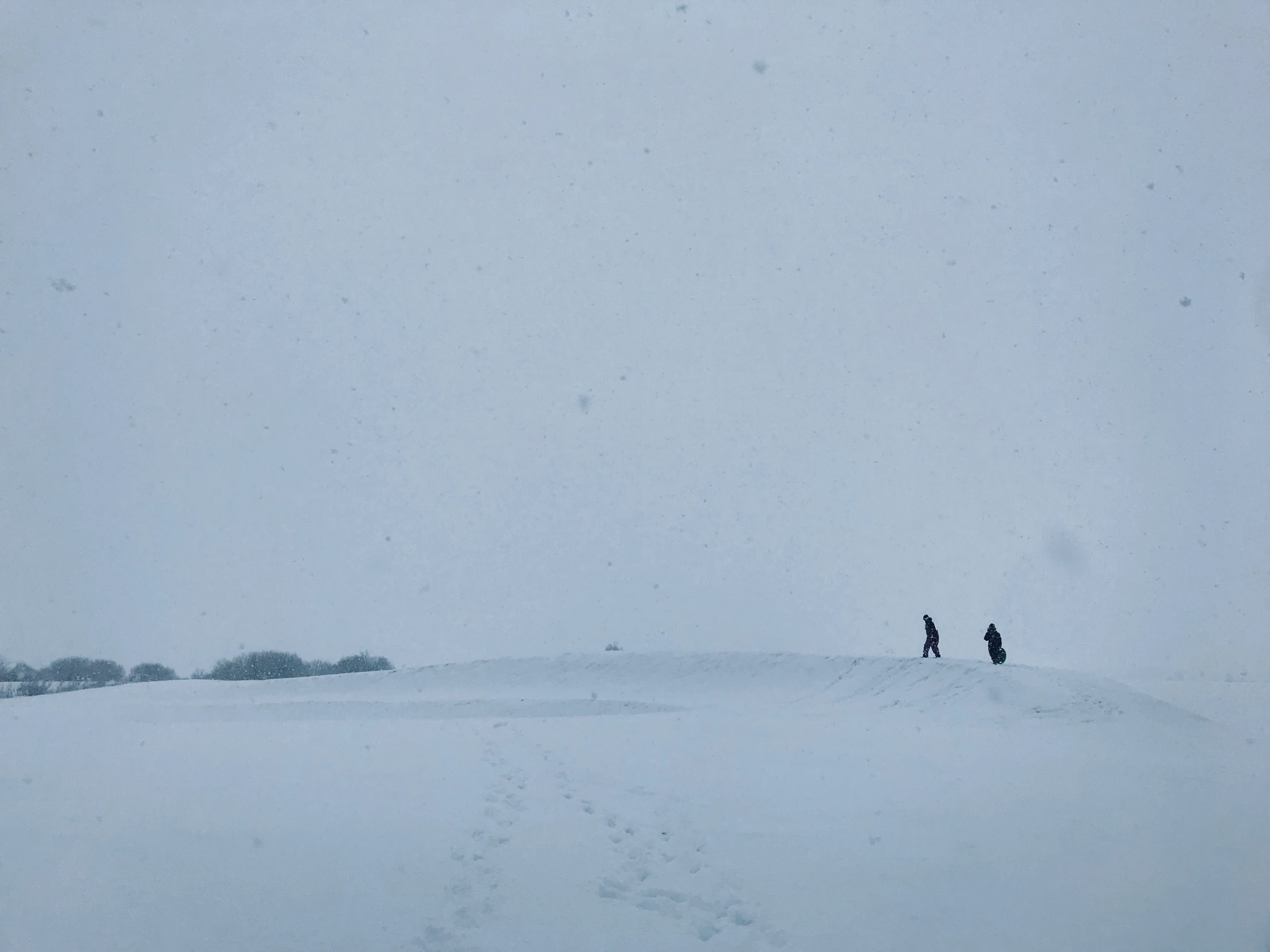 two people are standing on a large snowy hill