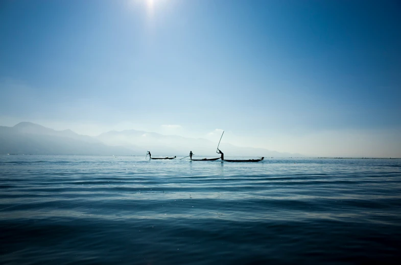 two boats sitting on the water near a mountain range