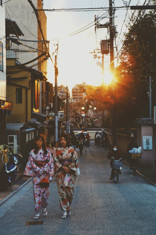 two woman in kimono walking on the street during sunset