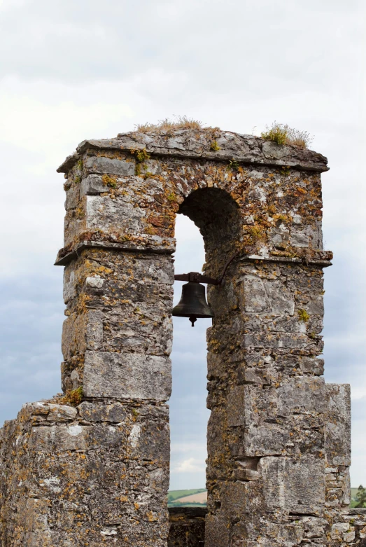 a bell stands on the ruins of a castle with a window