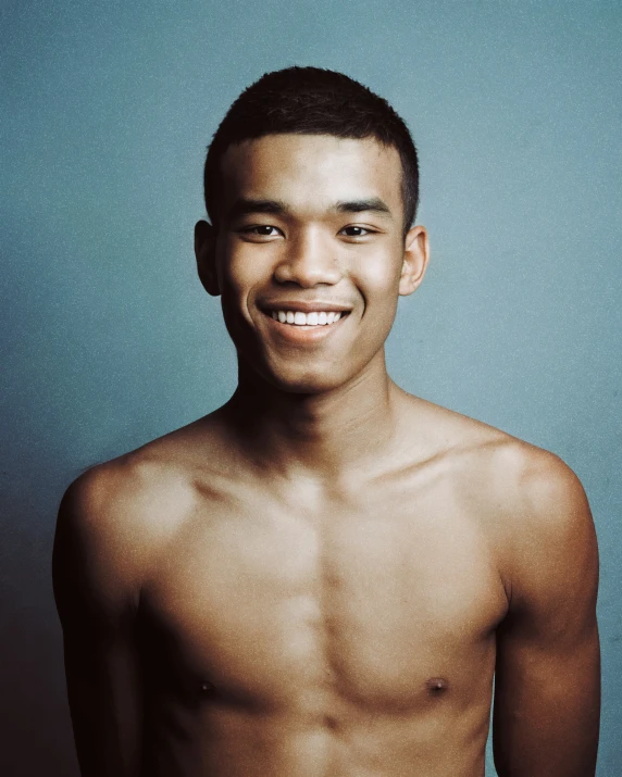 a man is smiling while he stands in front of a blue wall