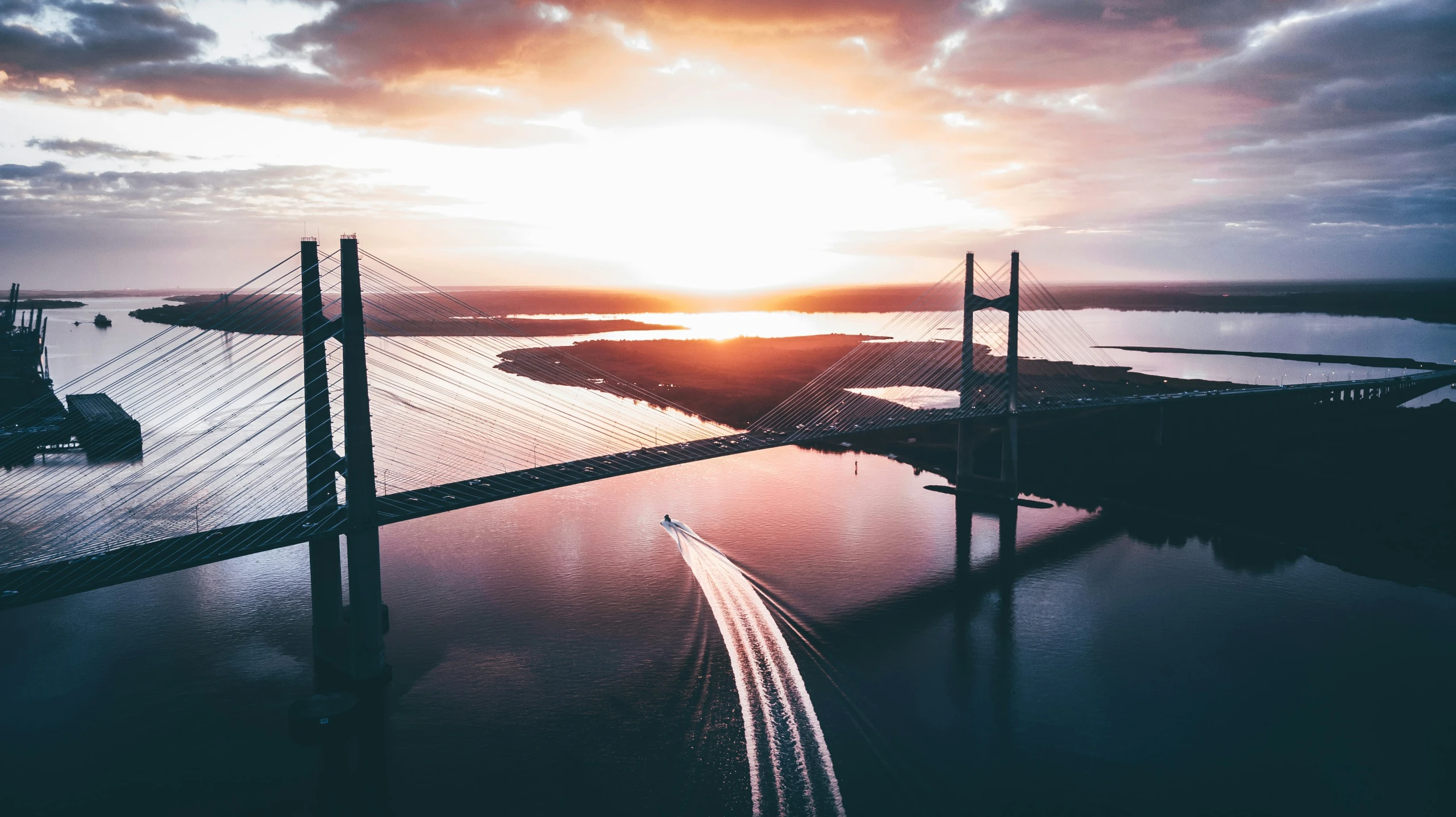 a sunset over a bridge with a body of water