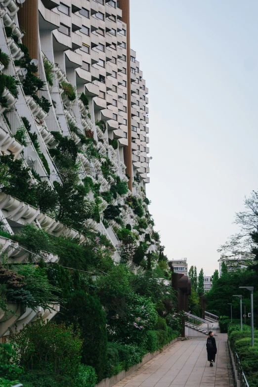 a person walking along a long walkway next to a tall building