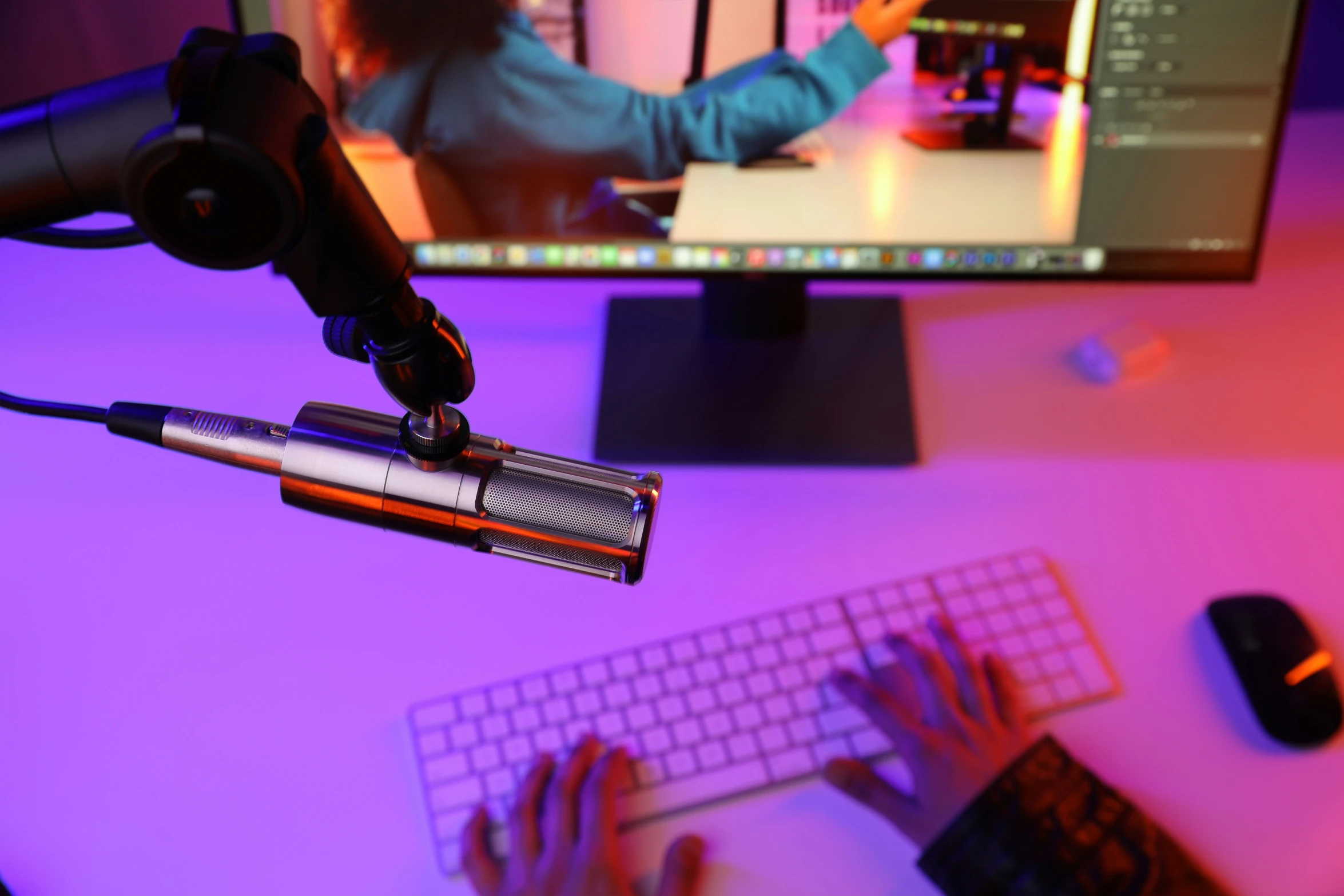 person with hand held up holding a computer microphone next to keyboard