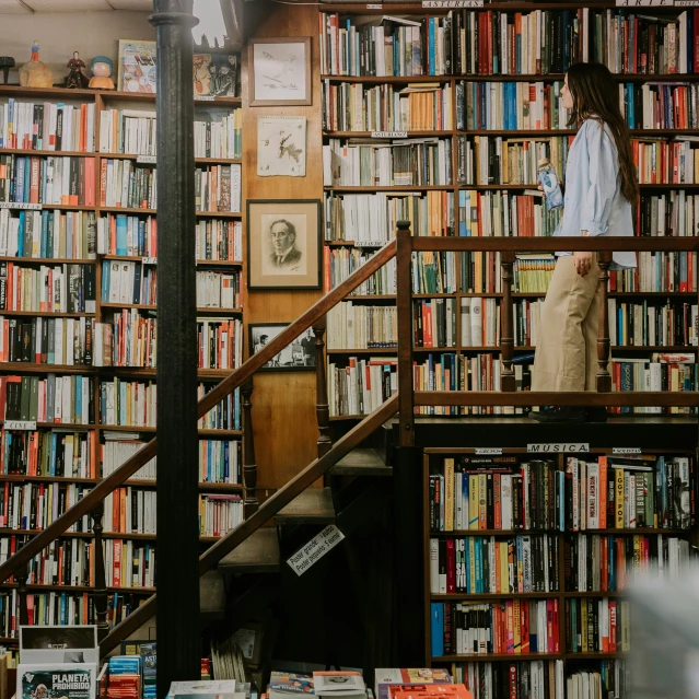 the woman is standing on the bookshelf in front of the staircase