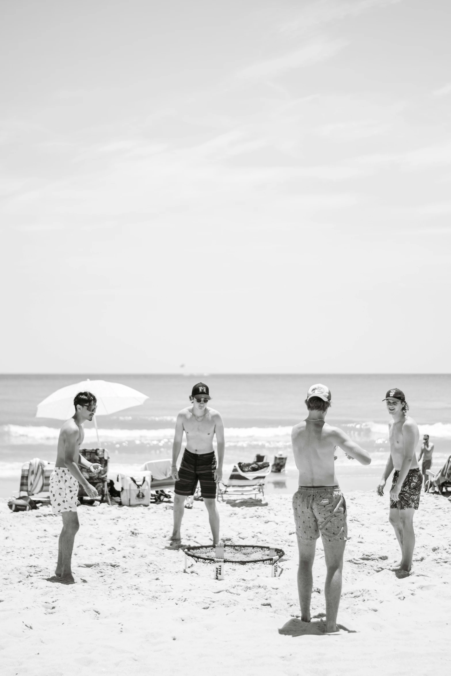 several people standing on the beach under an umbrella