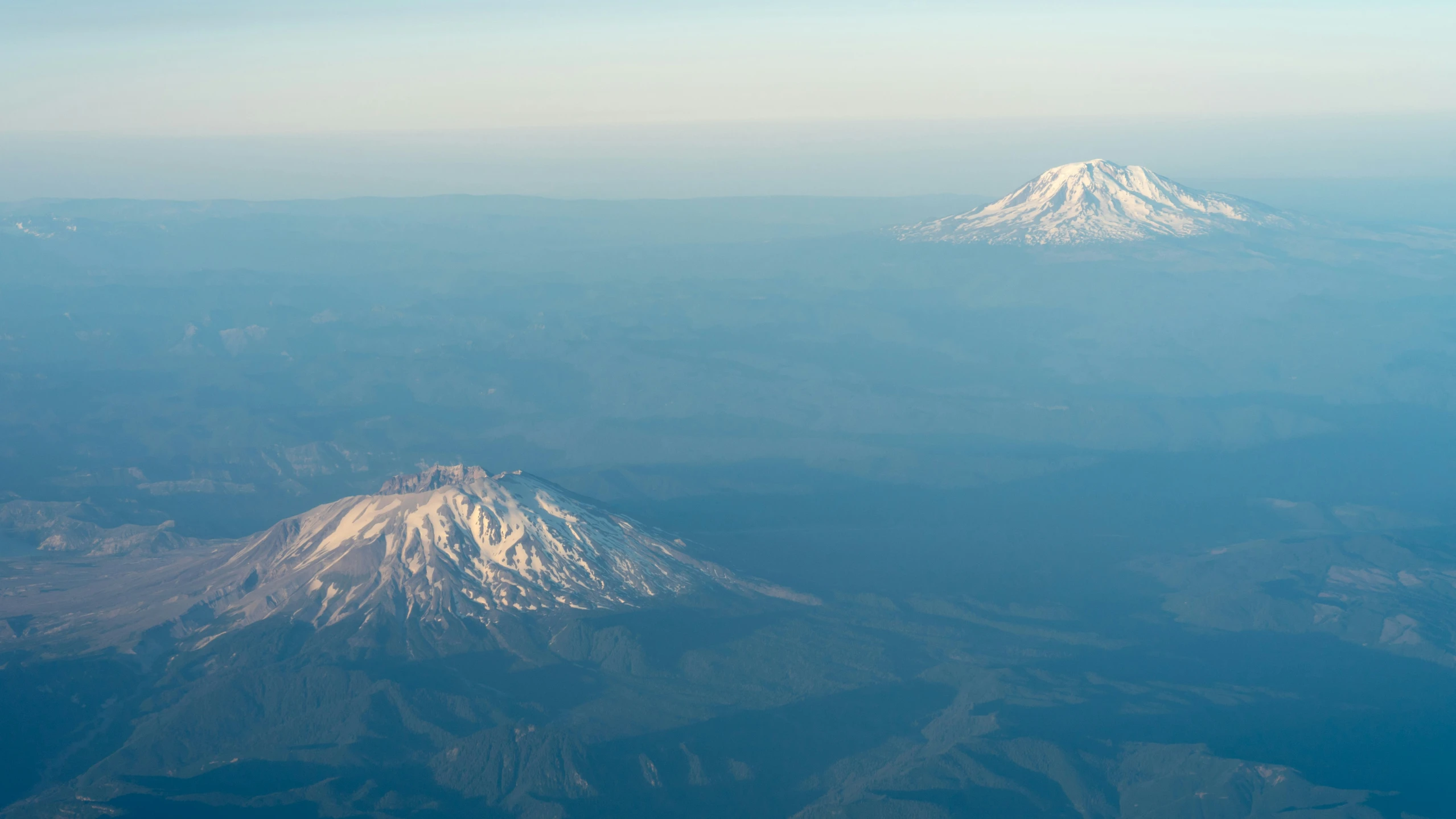 snow capped mountains in the distance are viewed from an airplane